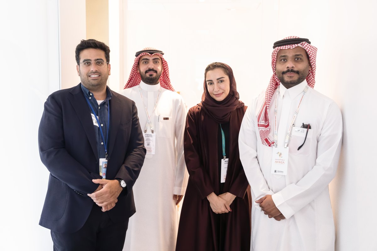 Four conference attendees posing together, wearing suits and traditional clothing