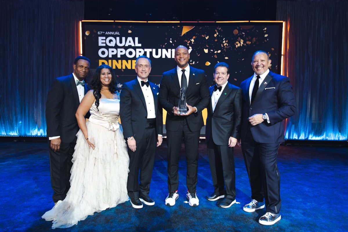 Six guests in formal attire posing with an award at the 67th annual Equal Opportunity Dinner