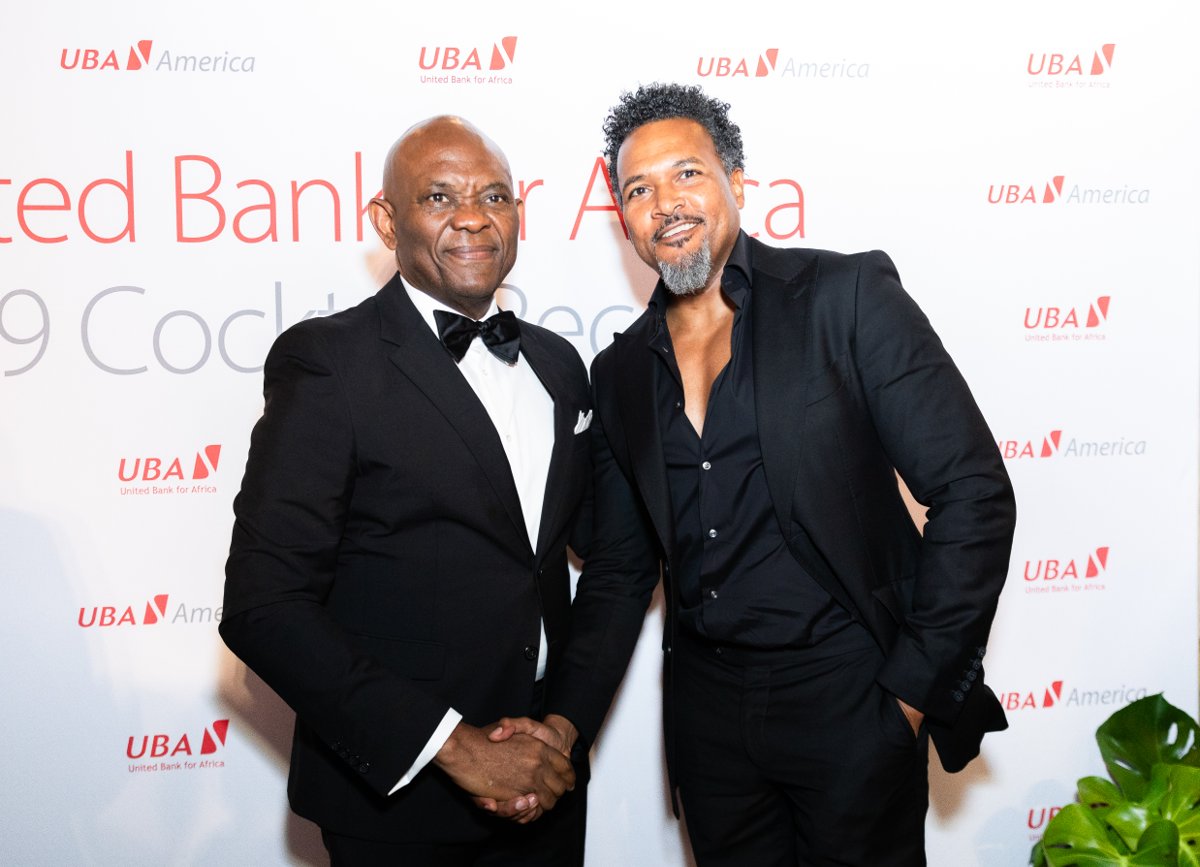 Two guests shaking hands in front of a UBA America event backdrop