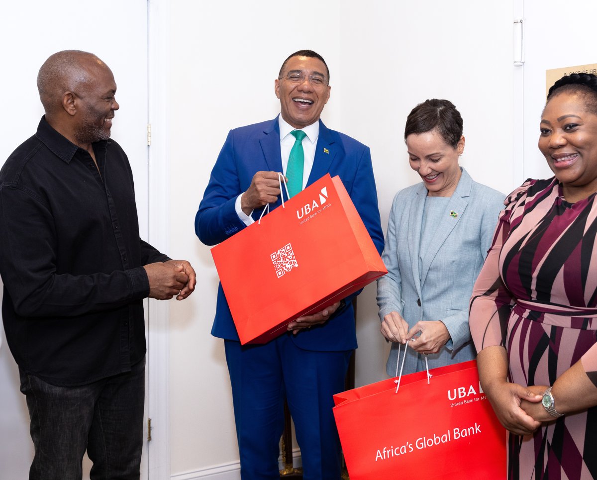 Four guests smiling and holding red UBA gift bags at a gathering