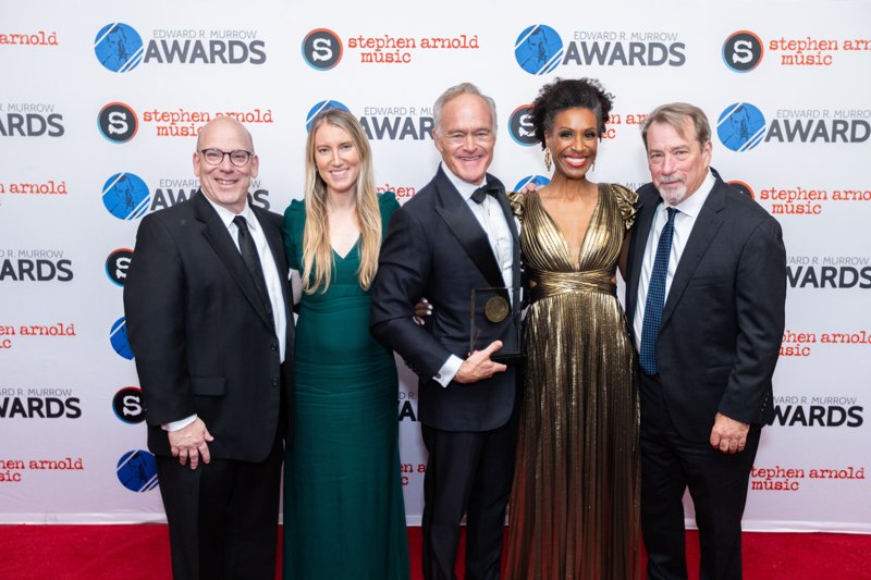 Five gala guests posing together with a Murrow Award against the event backdrop